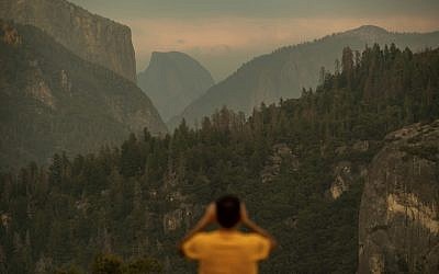 In this July 24, 2018, file photo, Francisco Avendano, visiting from Madrid, Spain, photographs Half Dome as smoke from the Ferguson Fire hangs over Yosemite National Park, Calif. (AP/Noah Berger)