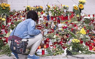 A woman knees in front of candles and flowers at the scene of an altercation in Chemnitz, Germany, August 31, 2018 (AP Photo/Jens Meyer)