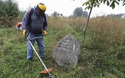 In this photo taken on August 29, 2018, Steven Reece, an ordained Southern Baptist minister who lives near Atlanta cleans an old Jewish cemetery in Rohatyn, the site of a Jewish Heritage project, close to Lviv, Ukraine, Aug. 29, 2018. (AP Photo/Yevheniy Kravs)