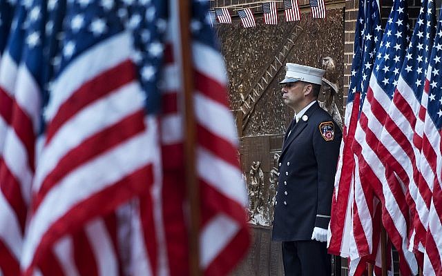 A New York City firefighter stands at attention by a memorial at the side of a firehouse adjacent to One World Trade Center and the 9/11 Memorial site during ceremonies on the anniversary of 9/11 terrorist attacks in New York on Tuesday, Sept. 11, 2018. (AP Photo/Craig Ruttle)