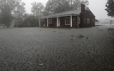A man makes a phone call from the front porch of his home surrounded bu floodwaters in Jacksonville, North Carolina after Hurricane Florence made landfall Sept. 15, 2018. (AP Photo/Chuck Burton)