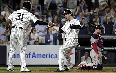 New York Yankees' Neil Walker, right, celebrates with Aaron Hicks (31) after hitting a three-run home run off Boston Red Sox relief pitcher Ryan Brasier during the seventh inning of a baseball game, Sept. 18, 2018, in New York. Red Sox catcher Christian Vazquez is at right. (AP Photo/Julio Cortez)
