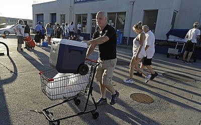 Kyle Crawford uses a shopping cart to carry bags of ice he purchased days after Hurricane Florence in Wilmington, NC, September 19, 2018. (AP Photo/Chuck Burton)