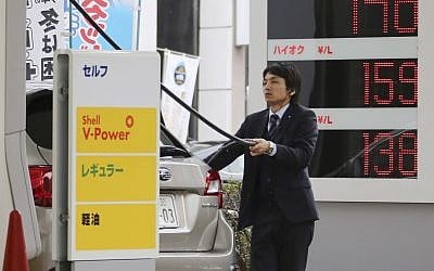 A man puts gas in his car at a Shell filling station in Tokyo Friday, Nov. 28, 2014. (AP/Koji Sasahara)