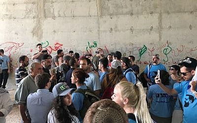 Israeli right-wing activists in blue shirts exchange shouts with Palestinian activists and local residents in a passageway under the Route 1 highway near the West Bank Bedouin village of Khan al-Ahmar, September 7, 2018. (Twitter screen capture) Israeli right-wing activists in blue shirts exchange shouts with Palestinian activists and local residents in a passageway under the Route 1 highway near the West Bank Bedouin village of Khan al-Ahmar, September 7, 2018. (Twitter screen capture)
