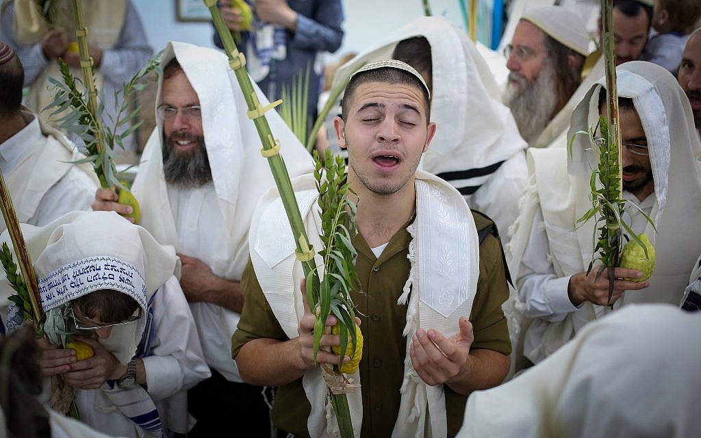 Jewish men wave the four species to mark the holiday of Sukkot during morning prayers at the Abuhav synagogue in the northern Israeli city of Safed on September 25, 2018. (David Cohen/Flash90)