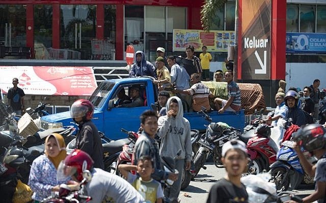 A family transports a coffin carrying a lost relative (background) as people loot a convenience store (foreground) in Palu, in Indonesia's Central Sulawesi province, on September 30, 2018. (AFP Photo/Bay Ismoyo) A family transports a coffin carrying a lost relative (background) as people loot a convenience store (foreground) in Palu, in Indonesia's Central Sulawesi province, on September 30, 2018. (AFP Photo/Bay Ismoyo)