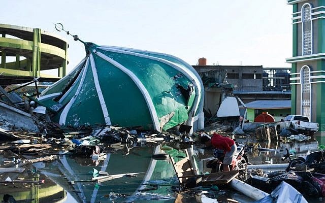 An earthquake victim salvages useable items near a collapsed mosque in Palu, in Indonesia's Central Sulawesi province, on October 1, 2018. (AFP Photo/Jewel Samad)