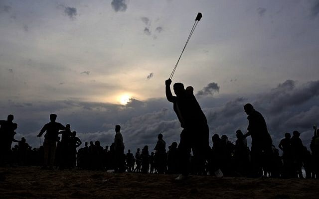 A Palestinian throws a stone toward Israeli forces during clashes on the beach near the maritime border with Israel, in the northern Gaza Strip, on October 1, 2018. (Said Khatib/AFP)