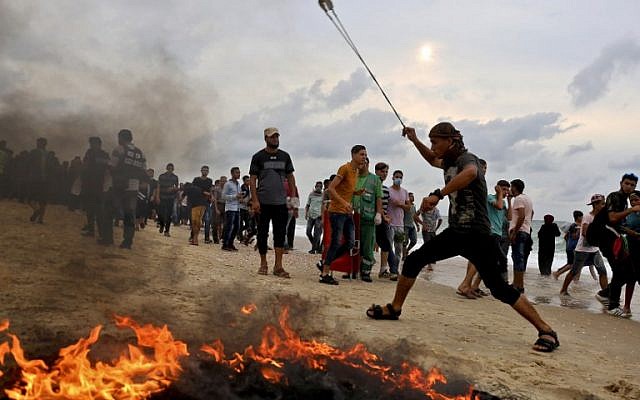 A Palestinian throws a stone towards Israeli forces during clashes on the beach near the maritime border with Israel, in the northern Gaza Strip, on October 1, 2018. (AFP PHOTO / SAID KHATIB) A Palestinian throws a stone towards Israeli forces during clashes on the beach near the maritime border with Israel, in the northern Gaza Strip, on October 1, 2018. (AFP PHOTO / SAID KHATIB)