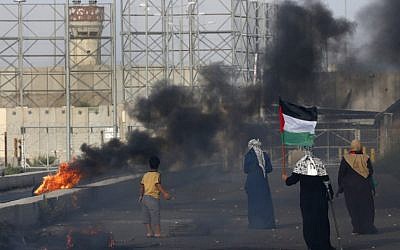 A Palestinian woman holds a flag as protesters demonstrate at the Erez border crossing with Israel in the northern Gaza Strip on October 3, 2018. (AFP/ Said KHATIB) A Palestinian woman holds a flag as protesters demonstrate at the Erez border crossing with Israel in the northern Gaza Strip on October 3, 2018. (AFP/ Said KHATIB)