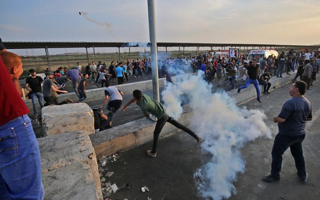 A Palestinian protester throws back a tear gas canister as people demonstrate at the Erez border crossing with Israel in the northern Gaza Strip on October 3, 2018. (AFP / SAID KHATIB)