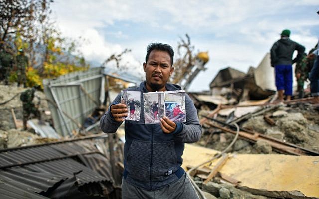 Rahmat Raidi, 26, shows portraits of his missing family members at Perumnas Balaroa village in Palu in Indonesia's Central Sulawesi on October 6, 2018, following the September 28 earthquake and tsunami (AFP PHOTO / MOHD RASFAN)