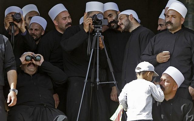 Members of the Druze community look through binoculars and telephoto cameras from their village of Majdal Shams in the Golan Heights across the border towards other community members on the Syrian side, during a rally on October 6, 2018 commemorating the 45th anniversary of the 1973 Arab-Israeli war (AFP PHOTO / JALAA MAREY)