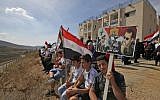 Members of the Druze community sit holding portraits of Syrian President Bashar Assad and Syrian national flags during a rally in the Druze village of Majdal Shams in the Israeli-annexed Golan Heights on October 6, 2018 commemorating the 45th anniversary of the 1973 Arab-Israeli war (AFP PHOTO / JALAA MAREY)