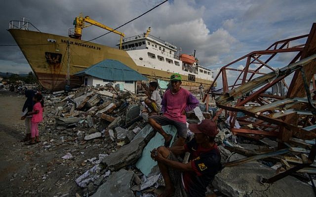 Residents sit near a washed out passenger ferry in Wani, Indonesia's Central Sulawesi on October 7, 2018, following the September 28 earthquake and tsunami (AFP PHOTO / MOHD RASFAN)