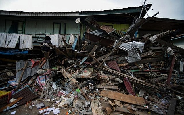 A resident climbs a badly damaged house in Wani, Indonesia's Central Sulawesi on October 7, 2018, following the September 28 earthquake and tsunami (AFP PHOTO / MOHD RASFAN) A resident climbs a badly damaged house in Wani, Indonesia's Central Sulawesi on October 7, 2018, following the September 28 earthquake and tsunami (AFP PHOTO / MOHD RASFAN)