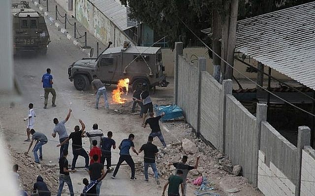 Palestinians throw stones and molotov cocktails at Israeli forces in the West Bank village of Shuweika on October 7, 2018. (AFP Photo/Jaafar Ashtiyeh)