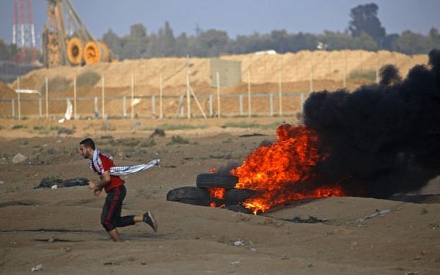 A Palestinian protester runs by burning tires at the Israel-Gaza border, east of Gaza city, on October 12, 2018. (Said KHATIB / AFP) A Palestinian protester runs by burning tires at the Israel-Gaza border, east of Gaza city, on October 12, 2018. (Said KHATIB / AFP)