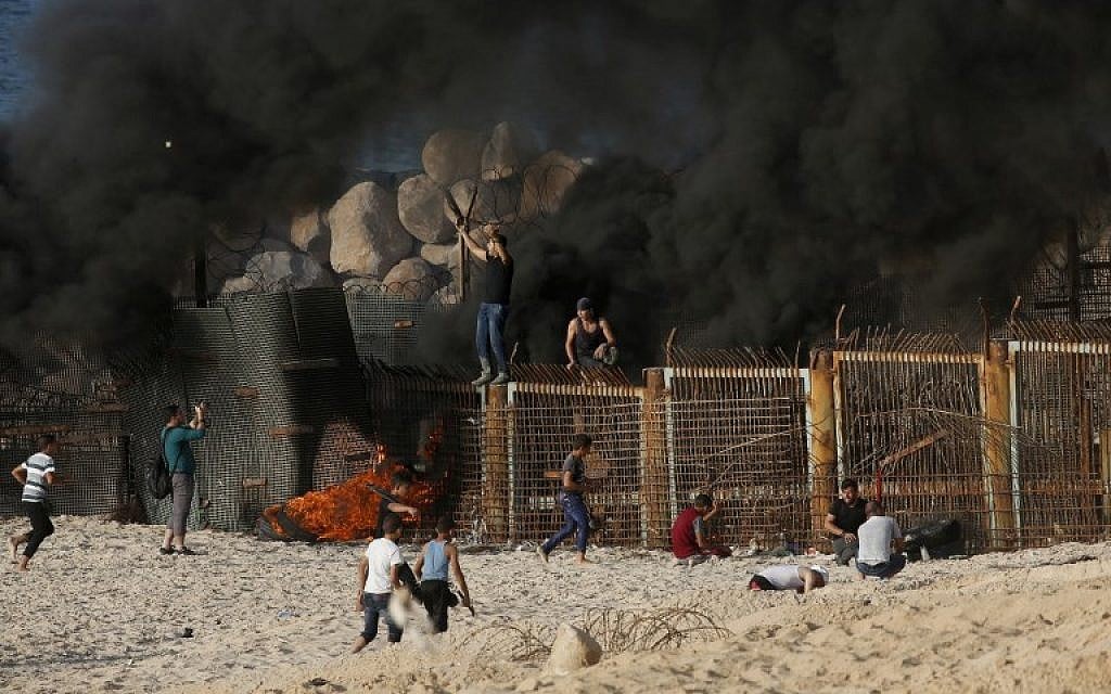Palestinian protesters climb a fence separating them from Israeli security forces during demonstration on the beach near the maritime border with Israel, in the northern Gaza Strip, on October 15, 2018. (Said KHATIB / AFP) Palestinian protesters climb a fence separating them from Israeli security forces during demonstration on the beach near the maritime border with Israel, in the northern Gaza Strip, on October 15, 2018. (Said KHATIB / AFP)