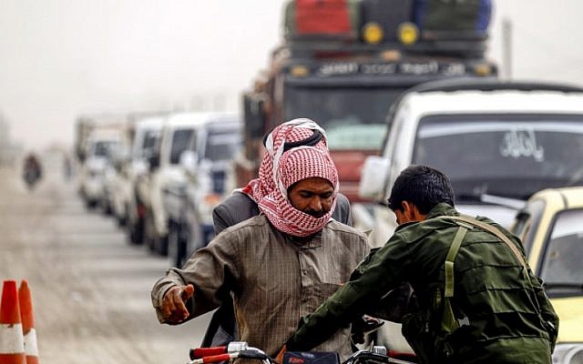 A member of the Raqqa civil council's local security forces inspects a motorcycle and its riders at a checkpoint securing vehicles entering into the eastern Syrian city and former Islamic State (IS) stronghold, on October 16, 2018. (Delil Souleiman/AFP)