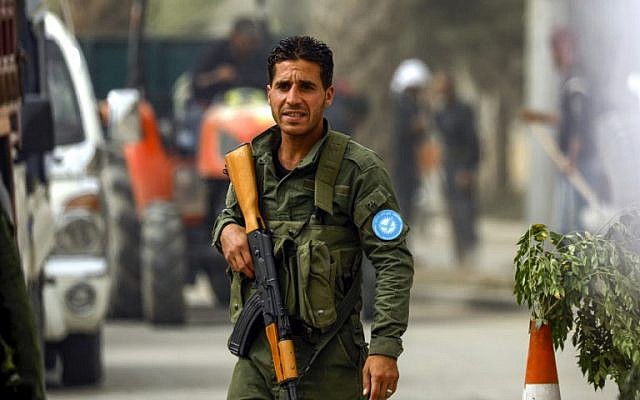A member of the Raqqa civil council's local security forces holds a Kalashnikov assault rifle as he stands at a checkpoint securing vehicles entering into the eastern Syrian city and former Islamic State (IS) stronghold, on October 16, 2018. (Delil Souleiman/AFP)