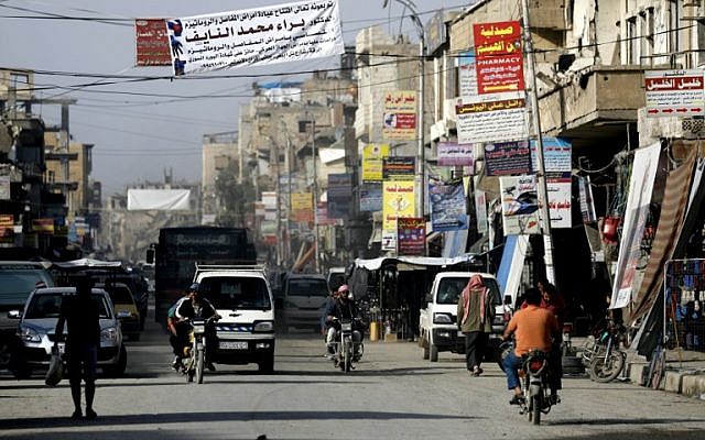 Banners advertising shops and clinics are pictured hanging in a street in the Syrian city of Raqqa on October 18, 2018. (Delil Souleiman/AFP)