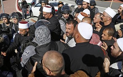 Israeli security forces stand guard as Druze men protest against municipal elections in front of a polling center in the village of Majdal Shams in the Golan Heights on October 30, 2018. (Photo by JALAA MAREY / AFP)
