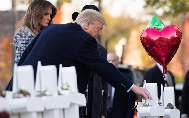 US President Donald Trump and First Lady Melania Trump, alongside Rabbi Jeffrey Myers, place stones and flowers on a memorial as they pay their respects at the Tree of Life Synagogue following last weekend's shooting in Pittsburgh, Pennsylvania, October 30, 2018. (Photo by SAUL LOEB / AFP)