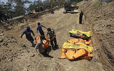 Indonesian police carry the body of a tsunami victim during a mass burial in Palu, Central Sulawesi, Indonesia, October 1, 2018 (AP Photo/Tatan Syuflana)