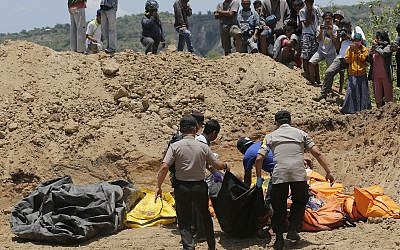 Rescue teams carry the bodies of victims to a mass grave following a major earthquake and tsunami in Palu, Central Sulawesi, Indonesia, Oct. 1, 2018 (AP Photo/Tatan Syuflana)
