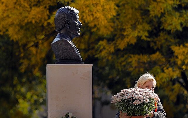A municipal worker carries flowers next to the bust of Holocaust survivor and Nobel laureate Elie Wiesel in Bucharest, Romania, October 9, 2018. (Vadim Ghirda/AP) A municipal worker carries flowers next to the bust of Holocaust survivor and Nobel laureate Elie Wiesel in Bucharest, Romania, October 9, 2018. (Vadim Ghirda/AP)