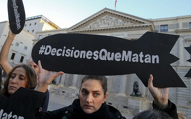 An activist holding a banner in the shape of a missile reading in Spanish "Decisions that kill" protests against the sale of weapons to Saudi Arabia in front of the Spanish Parliament in Madrid, Wednesday, Oct. 24, 2018. (AP Photo/Andrea Comas)