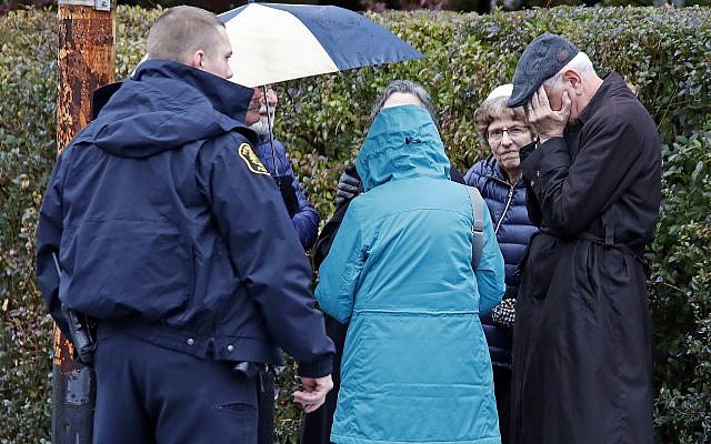 People gather on a corner near the Tree of Life Synagogue in Pittsburgh, Pa., where a shooter opened fire Saturday, Oct. 27, 2018, injuring multiple people. (AP Photo/Gene J. Puskar)