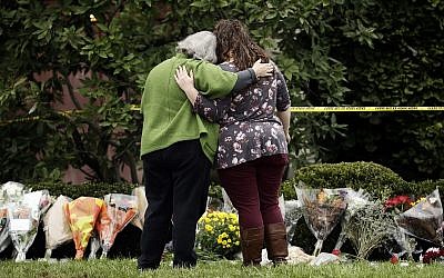 Two people support each other in front of flowers at a makeshift memorial at the Tree of Life Synagogue in Pittsburgh, Sunday, October 28, 2018. (AP Photo/Matt Rourke)