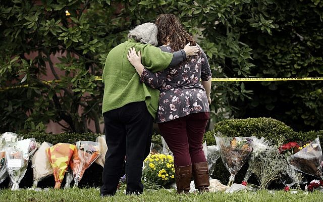 Two people support each other in front of flowers at a makeshift memorial at the Tree of Life Synagogue in Pittsburgh, Sunday, October 28, 2018. (AP Photo/Matt Rourke) Two people support each other in front of flowers at a makeshift memorial at the Tree of Life Synagogue in Pittsburgh, Sunday, October 28, 2018. (AP Photo/Matt Rourke)