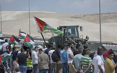 An Israeli army bulldozer passes by protesters flying Palestinian flags and chant anti Israel slogans while they try to block the traffic on the highway passing near the West Bank Bedouin community of Khan al-Ahmar on September 14, 2018. (AP Photo/Nasser Nasser) An Israeli army bulldozer passes by protesters flying Palestinian flags and chant anti Israel slogans while they try to block the traffic on the highway passing near the West Bank Bedouin community of Khan al-Ahmar on September 14, 2018. (AP Photo/Nasser Nasser)