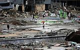 A man stands under an umbrella in a neighborhood of Wani village on the outskirts of Palu, Central Sulawesi, Indonesia, October 4, 2018. (Dita Alangkara/AP)