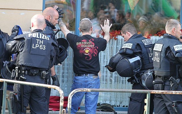 In this October 6, 2018 photo police officers search a visitor of a far right rock concert in Aploda, Germany. Slogan on the shirt reads 'guaranteed indexed'. (Sebastian Haak/dpa via AP) In this October 6, 2018 photo police officers search a visitor of a far right rock concert in Aploda, Germany. Slogan on the shirt reads 'guaranteed indexed'. (Sebastian Haak/dpa via AP)