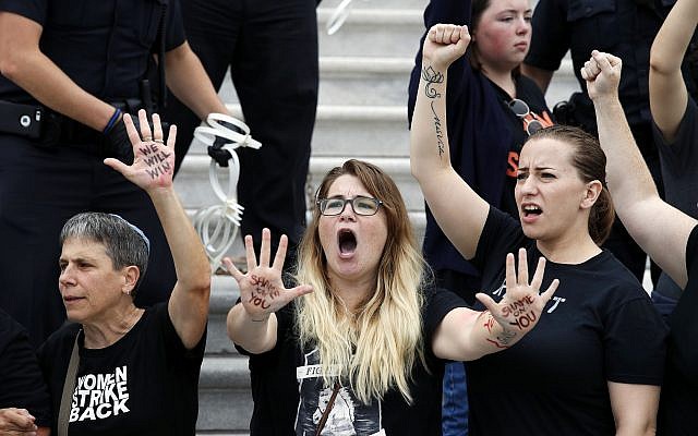 Activists chant as they are arrested by Capitol Hill Police officers after occupying the steps on the East Front of the US Capitol as they protest the confirmation vote of Supreme Court nominee Brett Kavanaugh on Capitol Hill, Oct. 6, 2018 in Washington. (AP Photo/Alex Brandon)