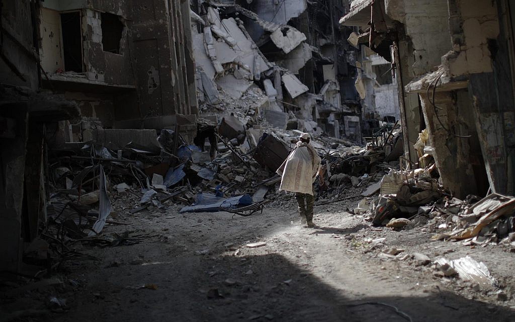 A man walks through rubble in the Palestinian refugee camp of Yarmouk in the Syrian capital Damascus, Syria, Saturday, Oct. 6, 2018 (AP Photo/Hassan Ammar)