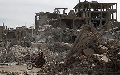 Syrian Soldiers ride a scooter through a devastated part of the in the Palestinian refugee camp of Yarmouk in the Syrian capital Damascus, Syria, Saturday, Oct. 6, 2018 (AP Photo/Hassan Ammar)