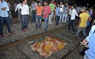 The body of a victim of a train accident lies covered in cloth on a railway track in Amritsar, India, Oct. 19, 2018 (AP Photo/Prabhjot Gill)