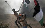 Palestinian protesters hurl stones at Israeli troops during a protest on the beach at the border with Israel near Beit Lahiya, northern Gaza Strip, Oct. 22, 2018. (AP Photo/Khalil Hamra)