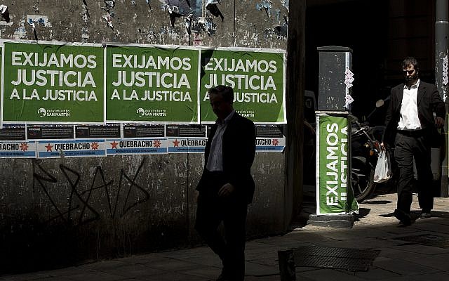 Men walk pass posters that read in Spanish "Demand justice to justice," in reference to march organized by federal prosecutors demanding justice after the death of special prosecutor Alberto Nisman, in Buenos Aires, Argentina, February 13, 2015. (AP Photo/ Rodrigo Abd/ File) Men walk pass posters that read in Spanish "Demand justice to justice," in reference to march organized by federal prosecutors demanding justice after the death of special prosecutor Alberto Nisman, in Buenos Aires, Argentina, February 13, 2015. (AP Photo/ Rodrigo Abd/ File)