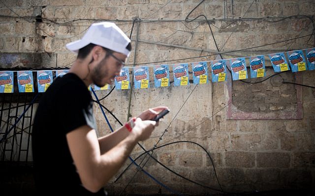 A man stands near posters of Jerusalem mayoral candidate Yossi Deitch outside the Mahane Yehuda market in Jerusalem on October 29, 2018, (Yonatan Sindel/Flash90)