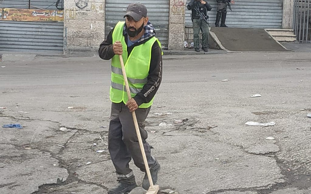 A Jerusalem sanitation worker sweeps a street in the Shuafat refugee camp on October 23, 2018. (Jerusalem municipality)