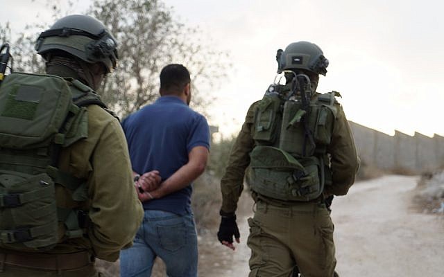 Israeli troops lead away a detained man during operations in the northern West Bank village of Shuweika on October 7, 2018. (Israel Defense Forces)