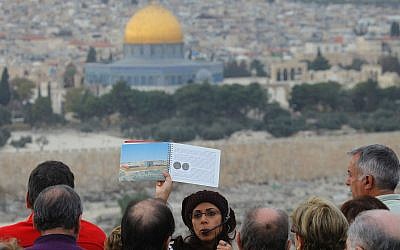 The Dome of the Rock in Jerusalem's Old City forms the backdrop to a tour guide holding up a picture of the ancient Jewish Temple. (Nati Shohat/FLASH90)