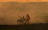 A Palestinian pulls another Palestinian on a wheelchair amid clouds of tear gas fired by Israeli forces during clashes east of Gaza City near the Israeli border on November 2, 2018. (Mahmud Hams/AFP)